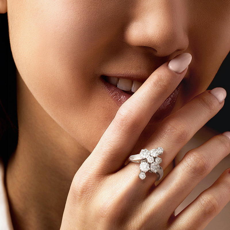 Diamond cluster ring on hand, openwork white gold band with round stone flower design