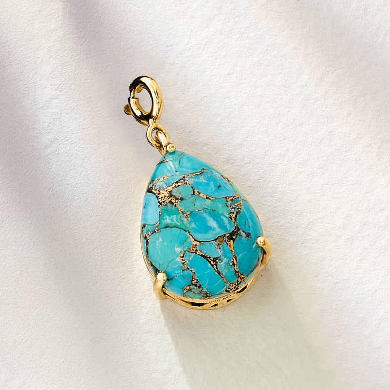 Pear-shaped turquoise charm with gold rim and small side bead accents