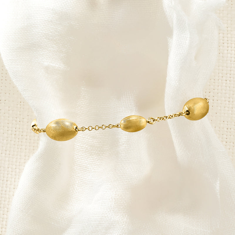 Gold oval bead station bracelet with small round end beads and chain