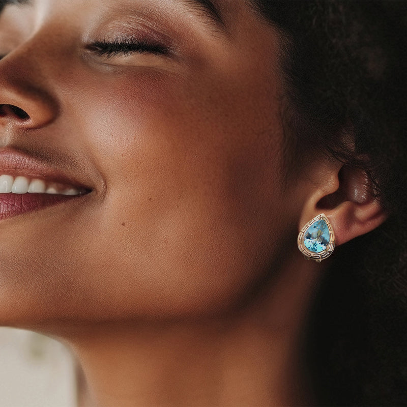 Blue topaz pear-cut stud earrings in yellow gold on model ear