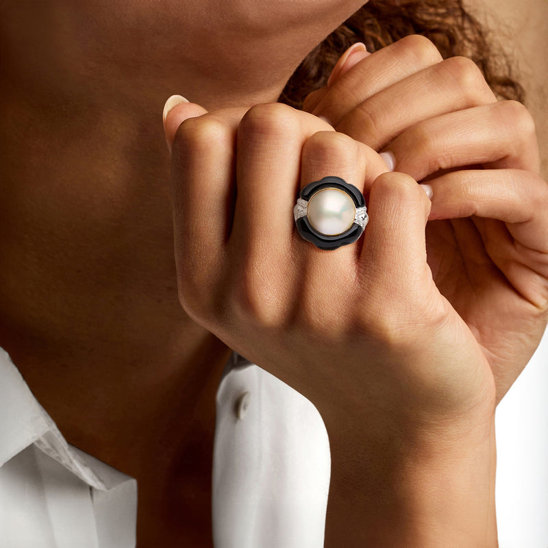 On-finger mabe pearl ring with black bezel, diamond accents, and yellow gold band