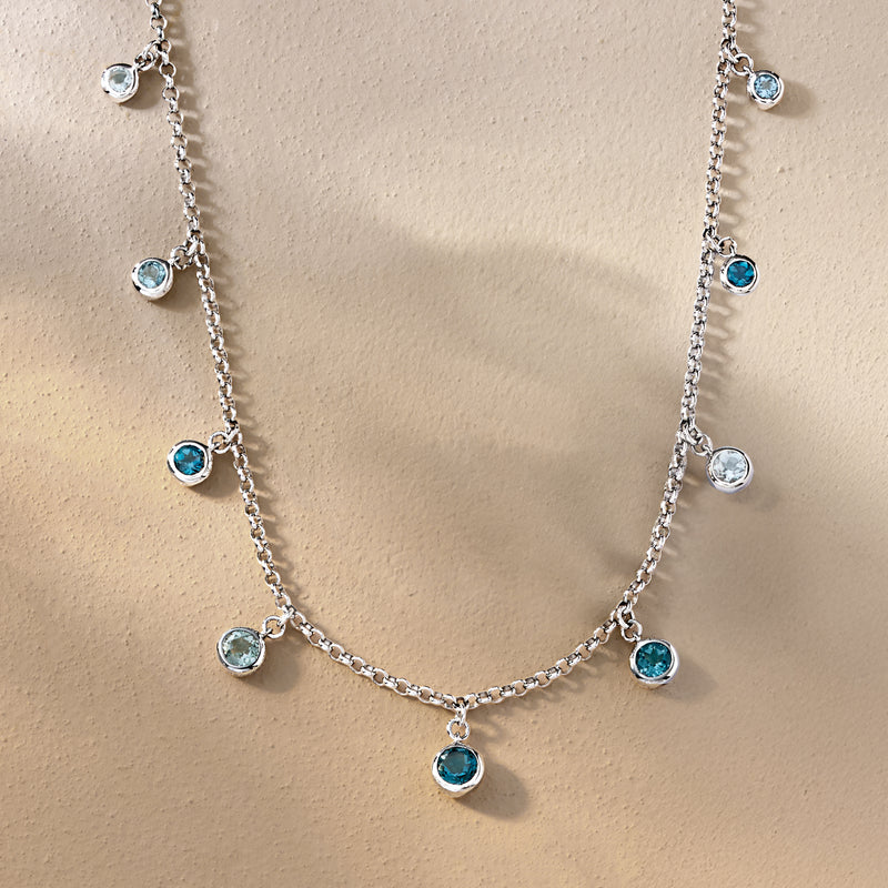 Sterling silver necklace featuring bezel-set round blue topaz drops along chain