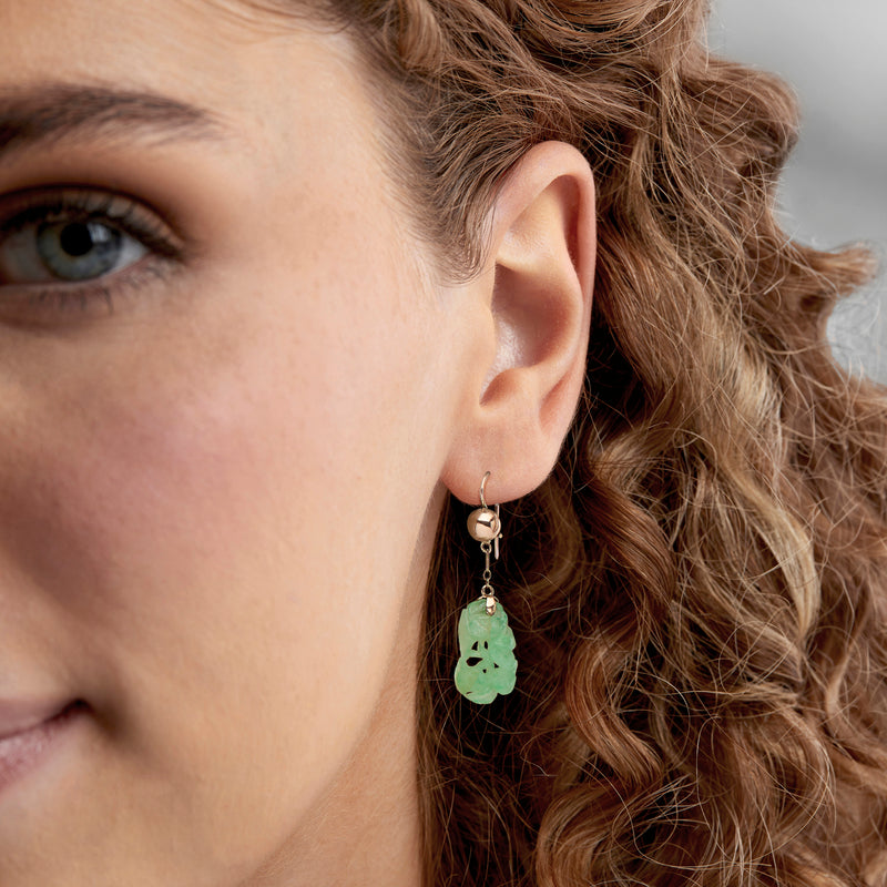 Carved green jade drop earrings in 10kt yellow gold earwires, worn close-up