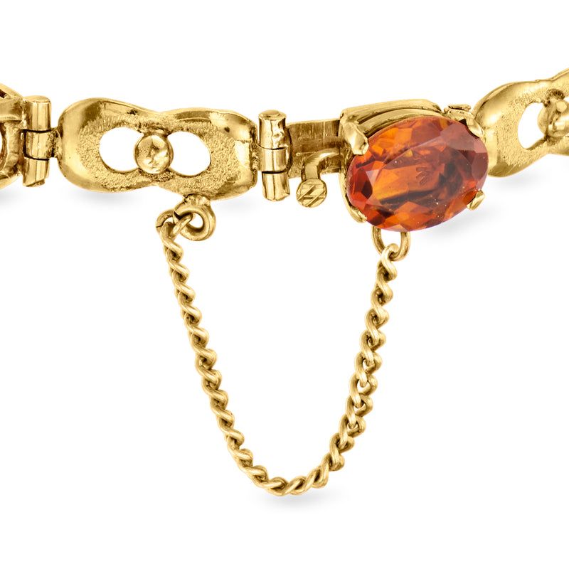 Yellow gold link bracelet with oval citrine centerpiece and dangling safety chain