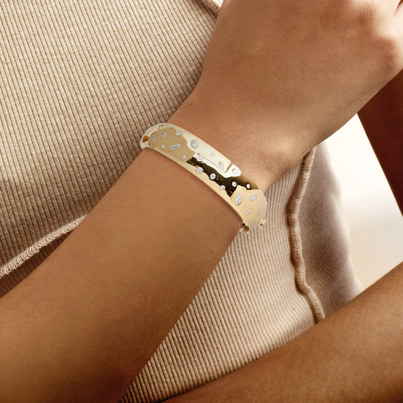 Gold diamond bangle bracelet on wrist with scattered round white stones