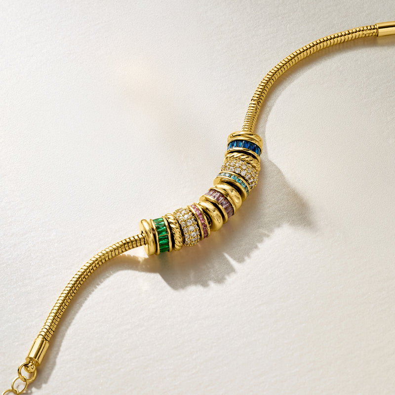Gold-plated bracelet close-up with blue, green, pink and clear stone cylinder beads