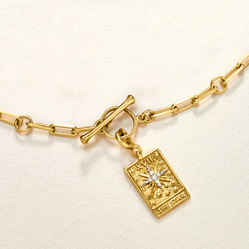 Gold chain necklace with dangling tarot card charm, starburst design, “THE STAR”