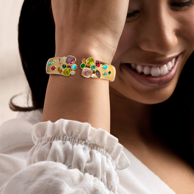 Gold-plated cuff bracelet with multicolored simulated gemstones worn on wrist