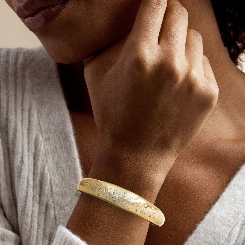 Yellow gold-plated bangle bracelet worn on wrist with clear CZs along the top