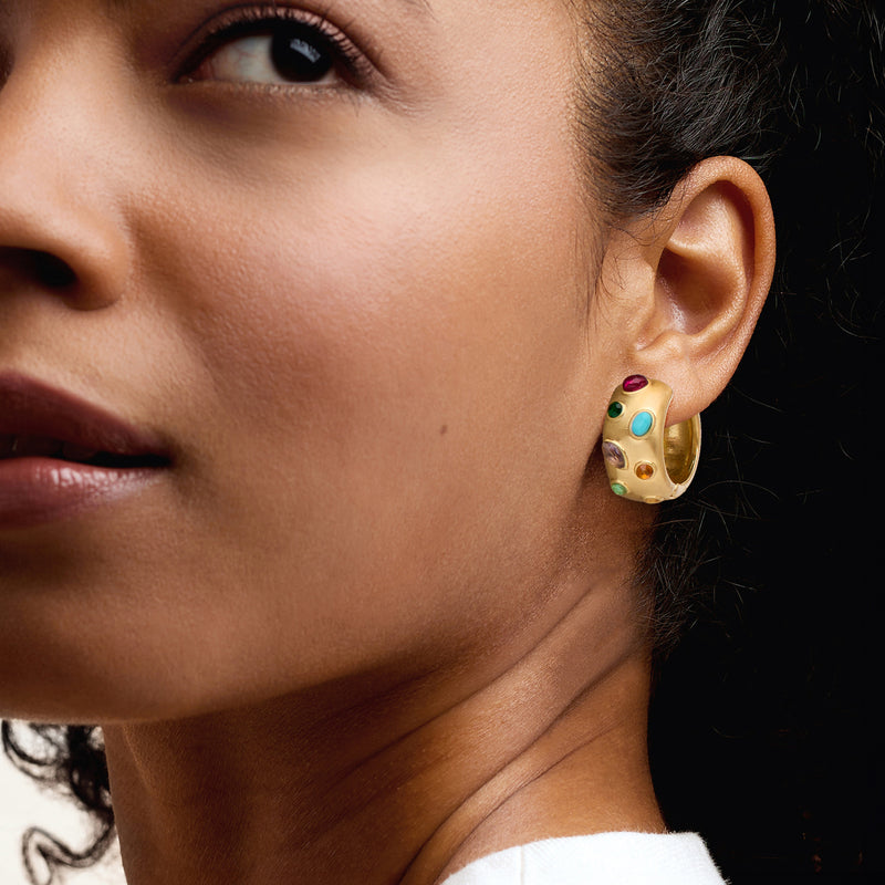 Gold-plated hoop earrings with multicolored simulated gemstones on model's ear