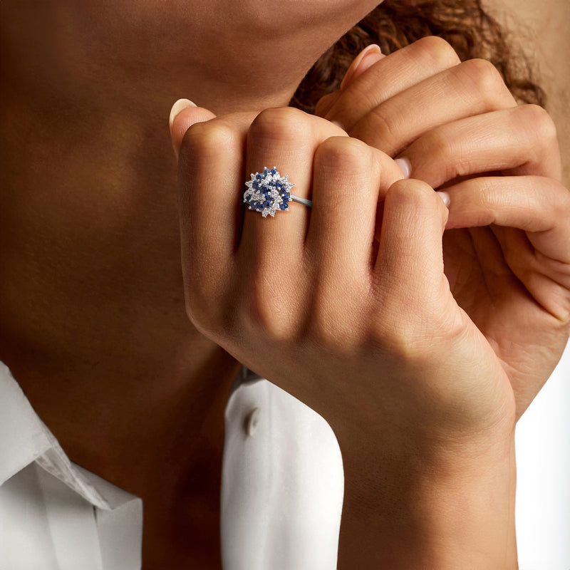 Blue sapphire and diamond halo swirl ring on hand, white gold band
