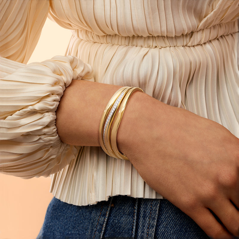 Gold diamond wave cuff bracelet worn on wrist with three stacked bands