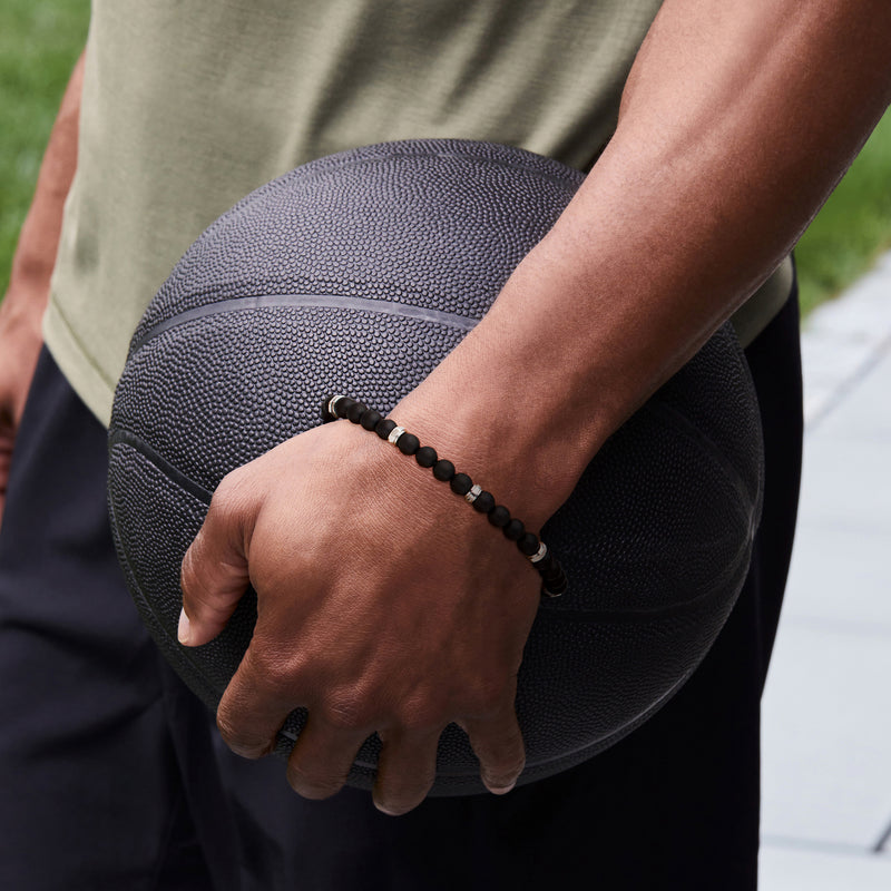 Men's black bead bracelet on wrist with small silver clasp detail