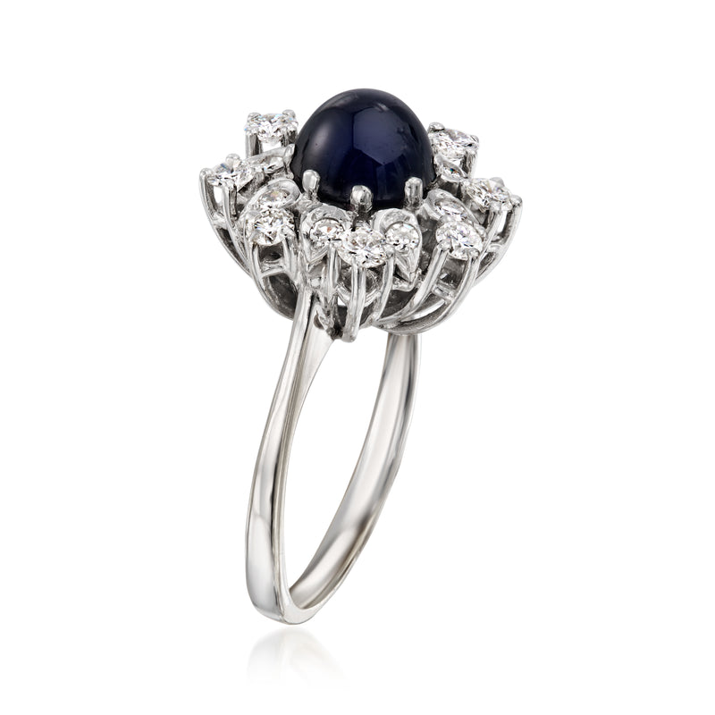 White gold ring with dark blue sapphire center and prong-set diamond cluster, side view