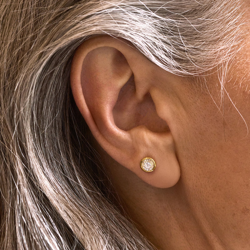 Round CZ stud earrings in 14kt yellow gold on ear, close-up