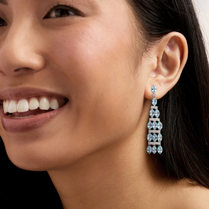 Model wearing aquamarine and diamond chandelier drop earrings with stacked oval rows