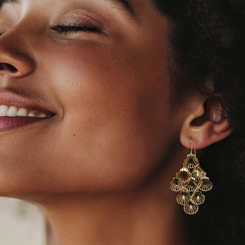 Yellow gold seashell chandelier earrings on ear with layered fan-shell drops
