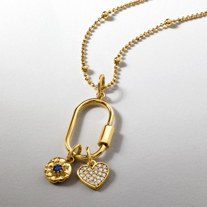 Gold oval carabiner pendant with heart charm and blue gemstone on chain