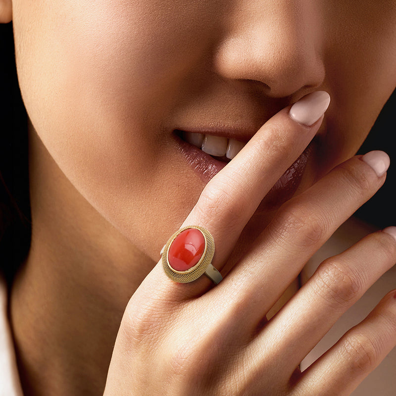 Oval coral cabochon roped ring in 18k yellow gold, on finger