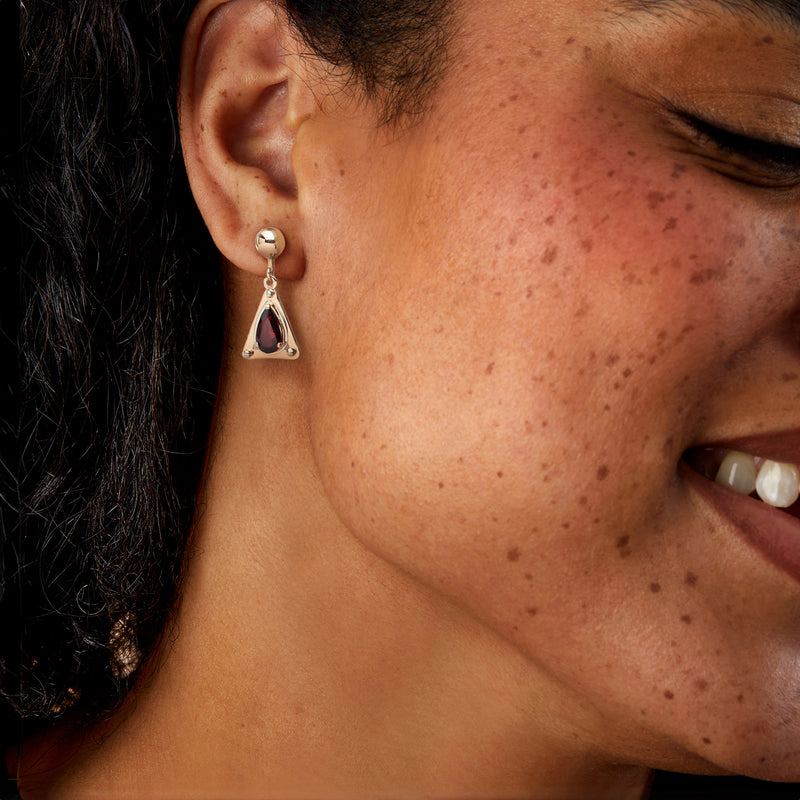 Triangular garnet drop earrings with red stone and diamond accents in yellow gold