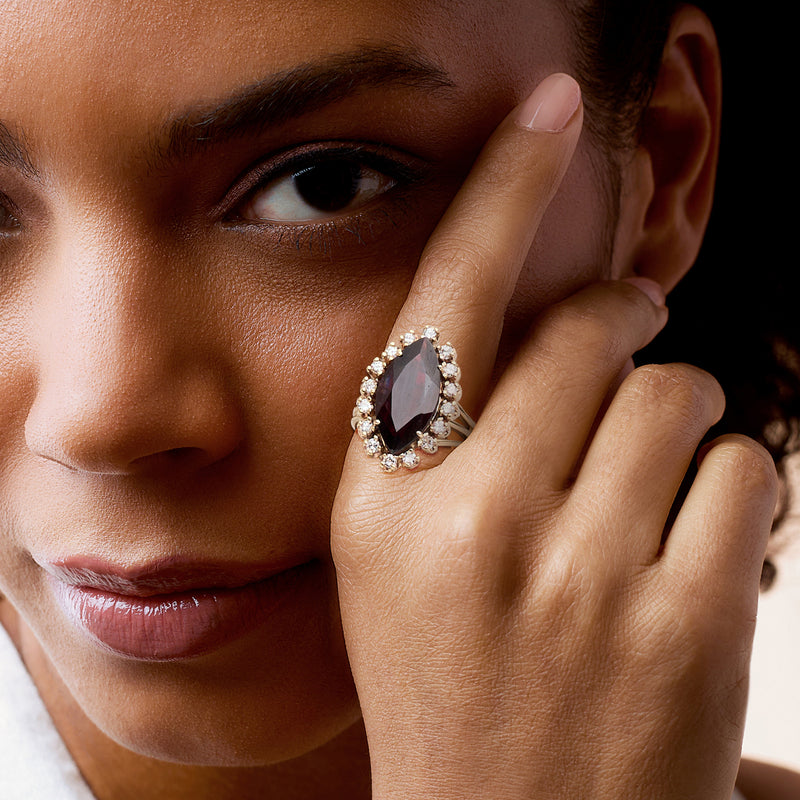 Garnet and diamond halo cocktail ring on hand, model close-up.