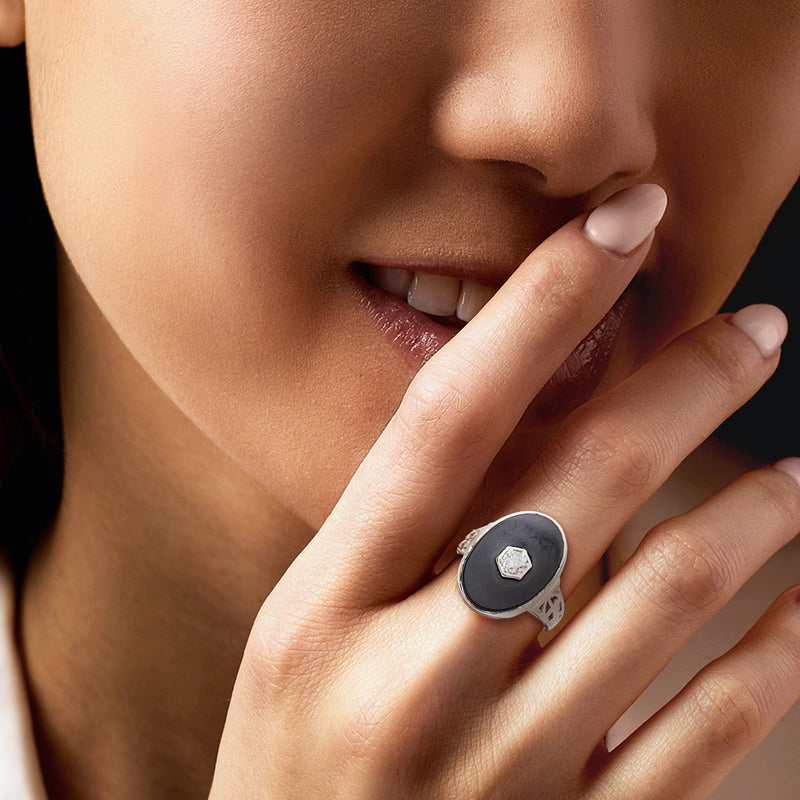 Onyx and diamond ring on finger, oval black bezel with small faceted diamond