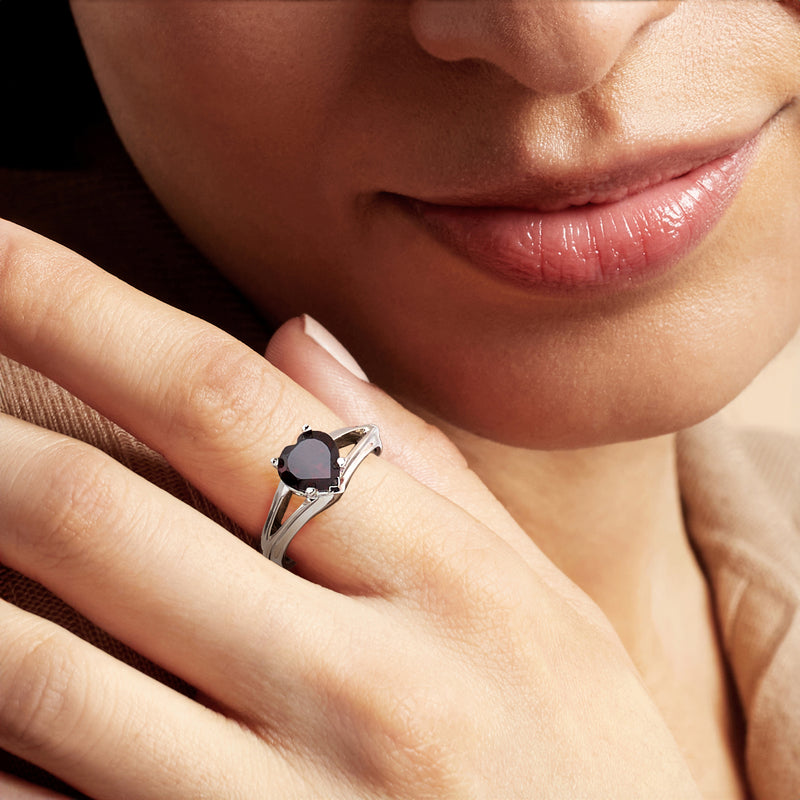 Sterling silver heart garnet ring on finger, close-up of dark red gemstone