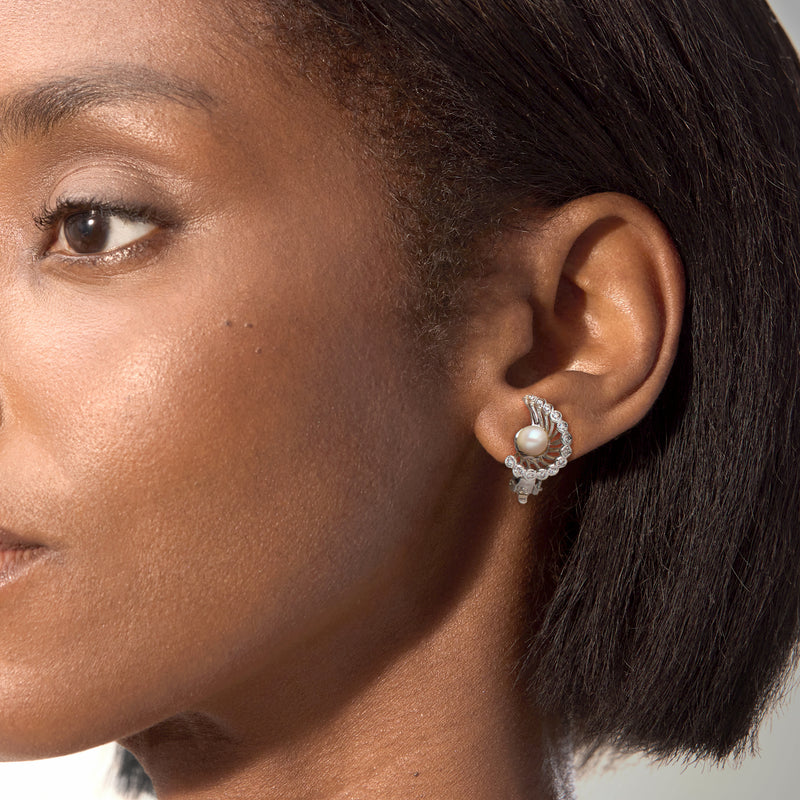 Cultured pearl and diamond swirl clip earrings on ear, round pearl in white gold