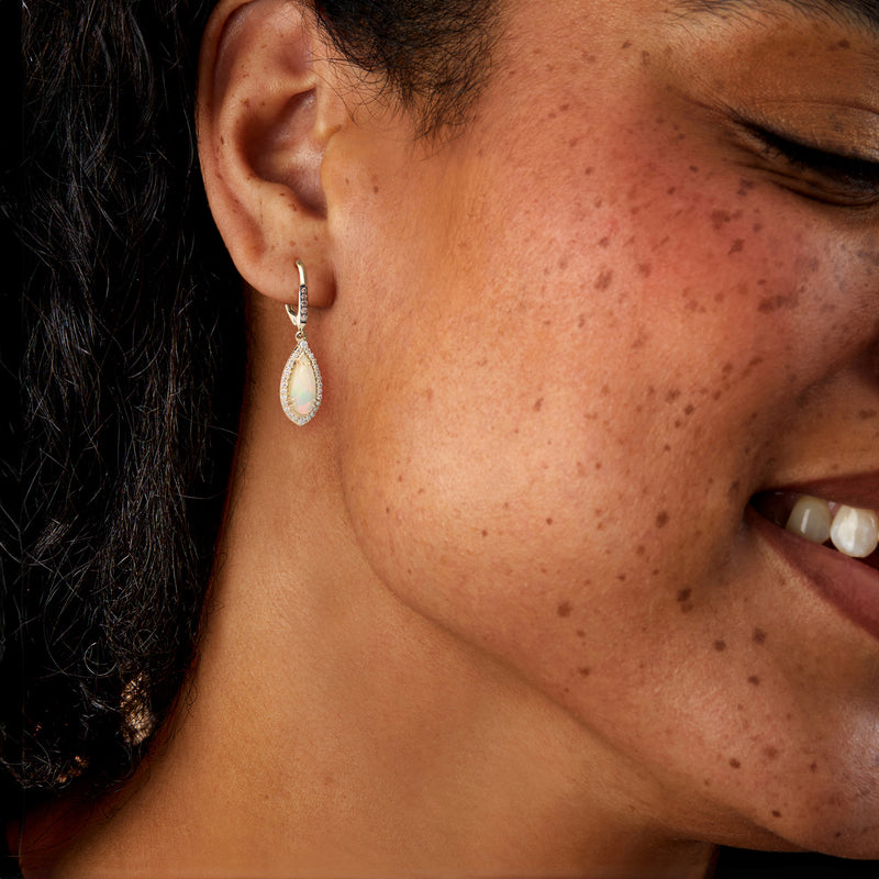 Opal teardrop drop earrings with diamond halo, leverback on model’s ear
