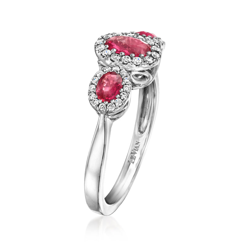 Three-stone halo ring with round pink-red center gems, diamond accents, slim gold band