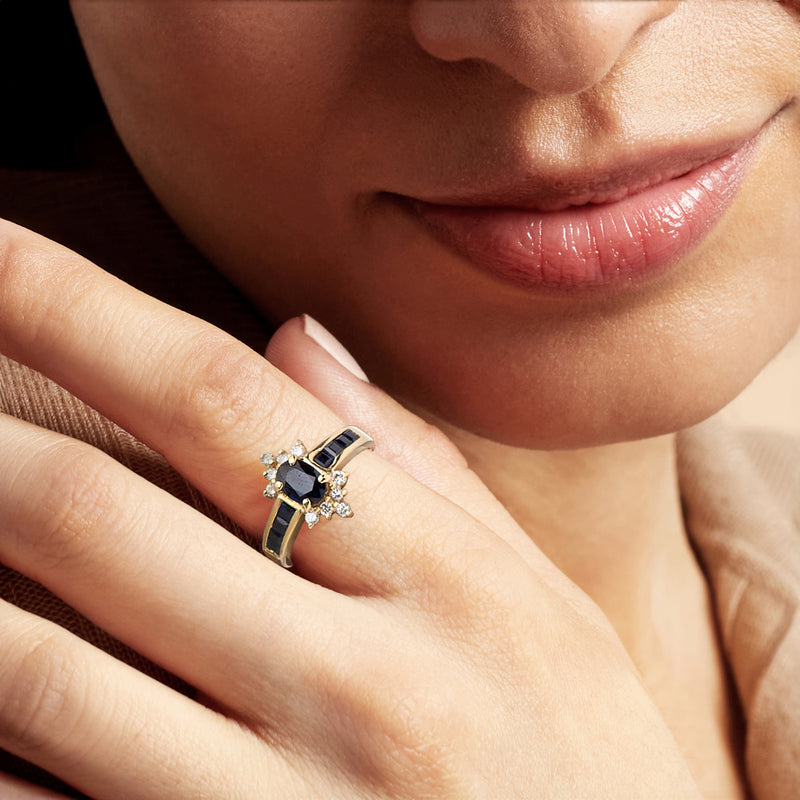 Close-up of blue sapphire and diamond ring on finger in 14kt yellow gold setting