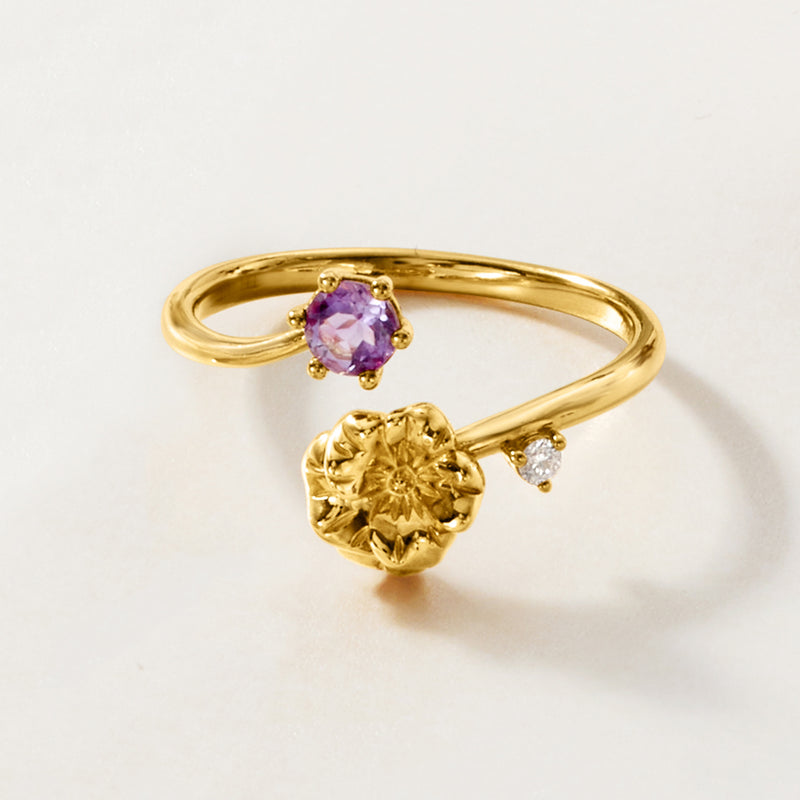 Gold tone ring with purple amethyst oval on top and floral band with clear diamond