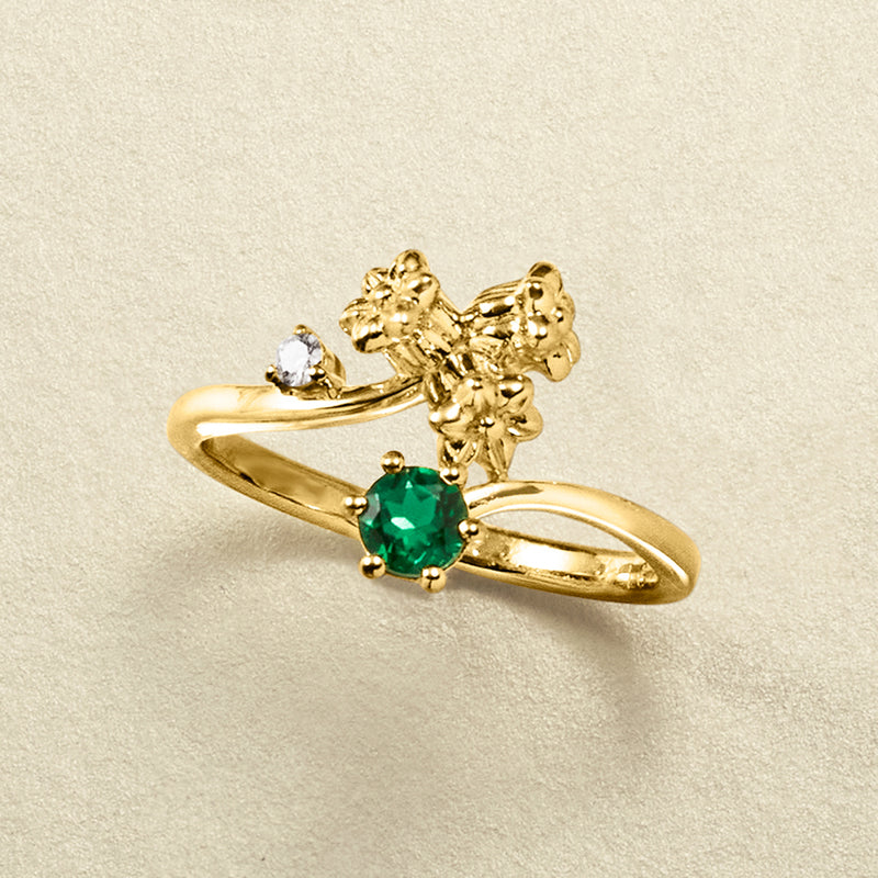 Gold lily of the valley ring close-up: green emerald center with two small round diamonds