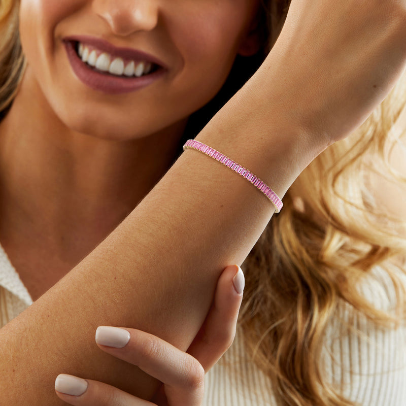 Pink gemstone tennis bracelet on wrist with slim gold clasp