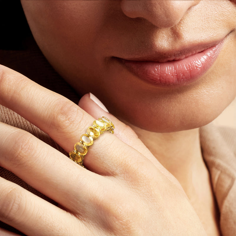 Yellow gold eternity band with oval yellow sapphire stones on finger