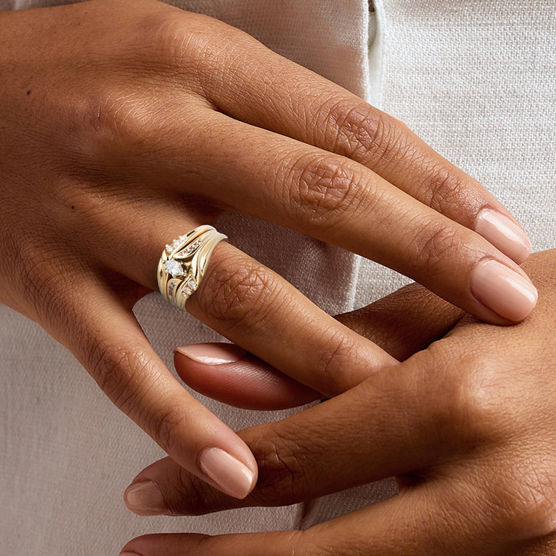 Yellow gold diamond bridal ring on hand with oval center and round stones