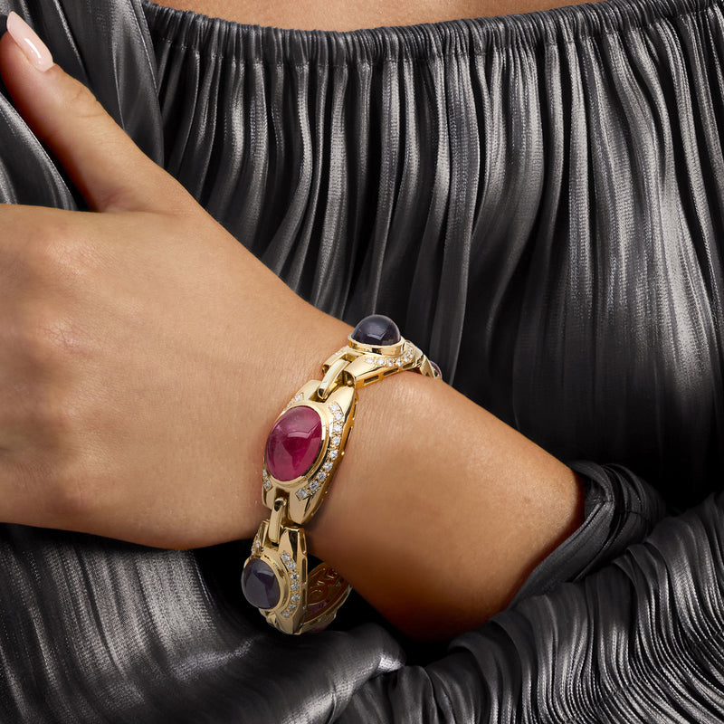 18k yellow gold bracelet worn on wrist with oval pink center gemstone and dark stones