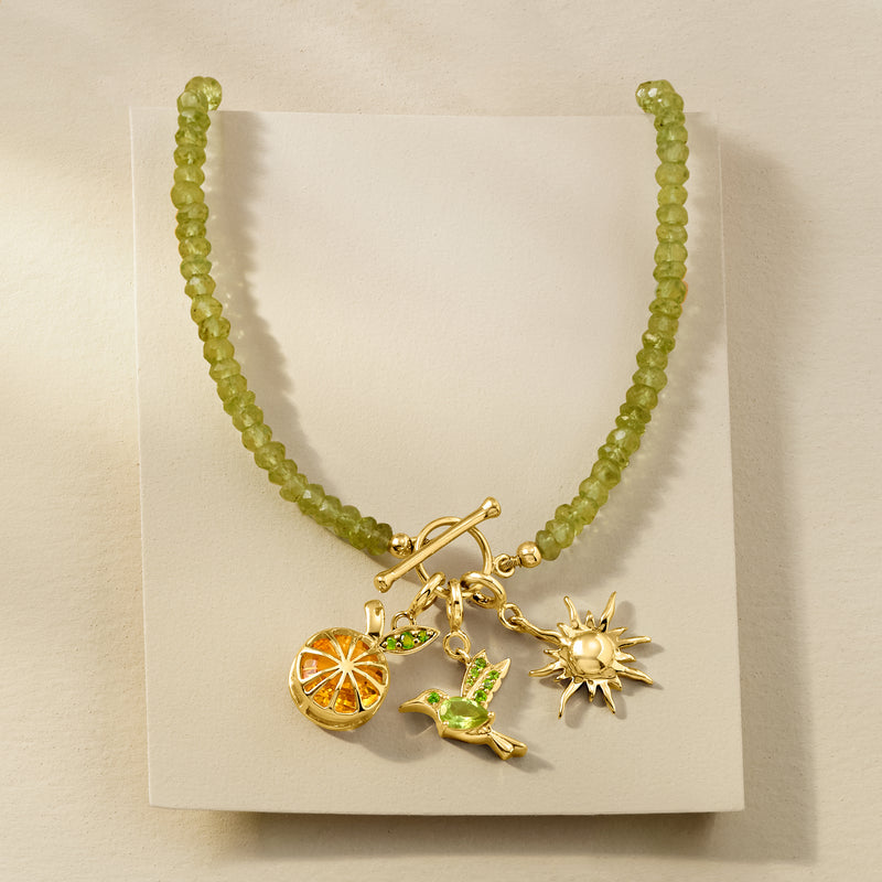 Gold necklace on display with green bead chain and hummingbird charm