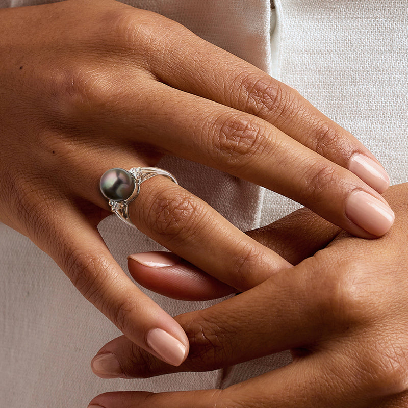 Cultured pearl and diamond ring on hand, round dark pearl with openwork band