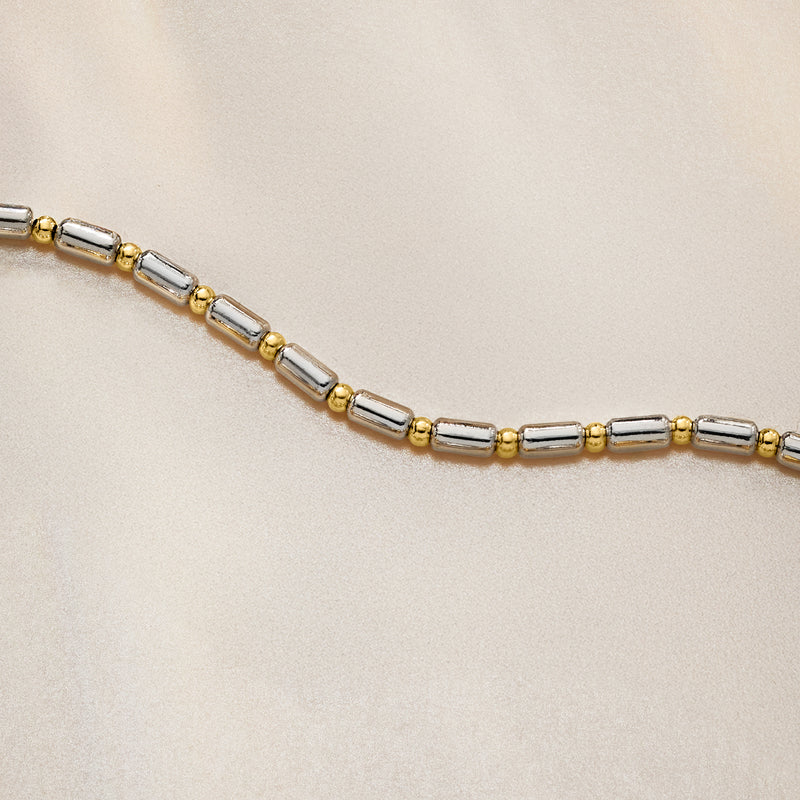 Close-up of dot-and-dash station bracelet links in silver with gold accents
