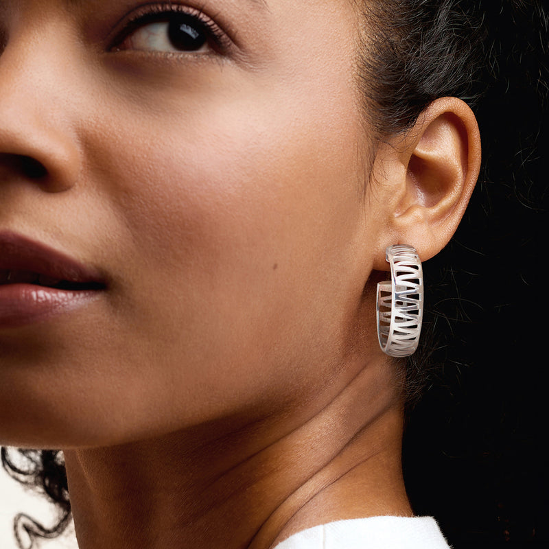 Sterling silver zigzag hoop earrings on ear, ribbed zigzag band with hinge