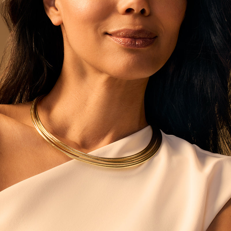 Gold multi-strand flex necklace worn at the neckline, layered curved chains