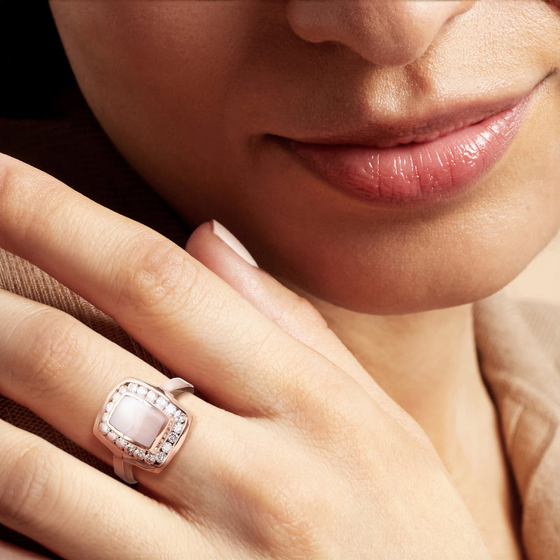 Rose gold ring with mother-of-pearl center and diamond halo on finger