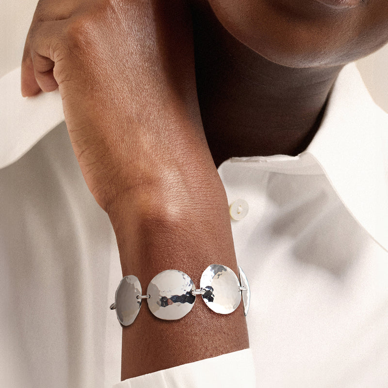Hammered disc-link bracelet on wrist with three textured silver discs and metal clasp