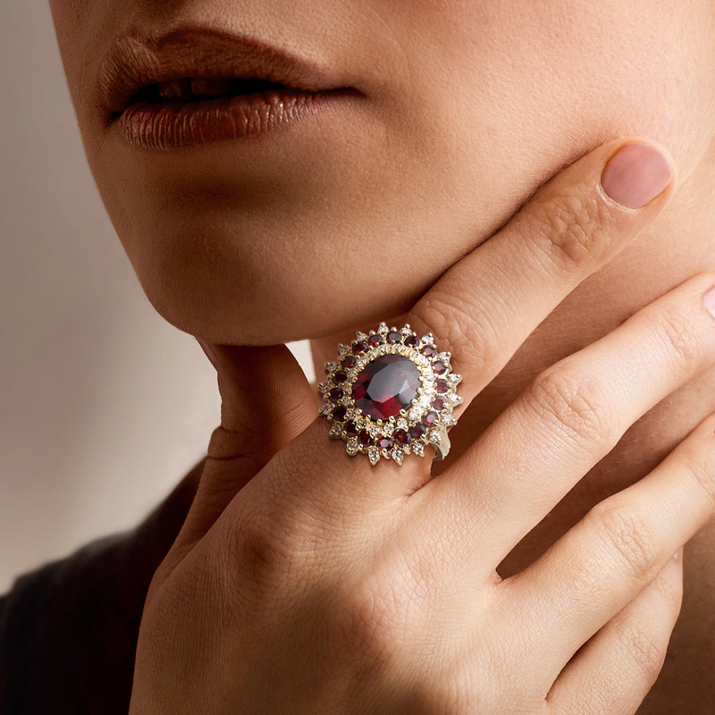 Red garnet and diamond cluster ring in 18kt yellow gold on a hand close-up