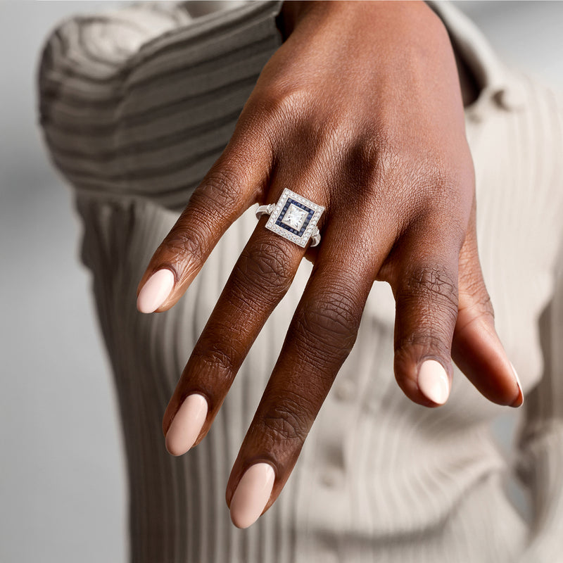 Platinum square diamond ring with blue sapphire accents worn on hand