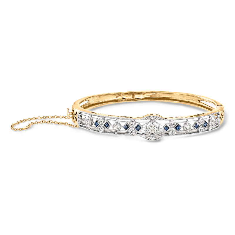 Platinum bangle bracelet with filigree pattern, clear diamonds and blue sapphire accents