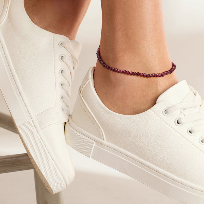Garnet bead anklet worn on ankle with round red beads and gold-tone clasp