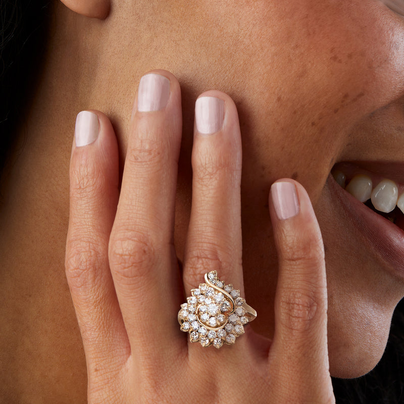 Yellow gold diamond swirl ring on hand, clustered round stones halo