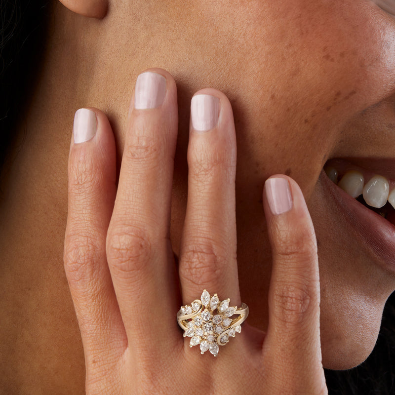 Yellow gold diamond cluster ring on finger with marquise and round stones